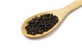 Closeup of black pepper grains on a wooden spoon isolated over white background Royalty Free Stock Photo