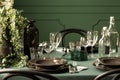 Closeup of black plates, flowerpot and water bottles on dining room table with green tablecloth Royalty Free Stock Photo