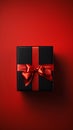 A closeup of a black and red gift box with a ribbon and a monoch