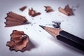 Closeup of black sharp pencil with wooden swirl  shavings after sharpening with a sharpener on white paper with copyspace Royalty Free Stock Photo