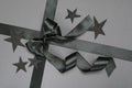 Closeup of black shiny ribbon and bow, decorative stars on the grey surface