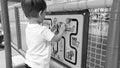 Closeup black and white portrait of adorable toddler boy playing with wooden toy puzzle on the children palyground