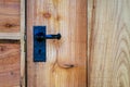 Closeup of black wrought iron door handle on waney edge wooden shed door. Royalty Free Stock Photo