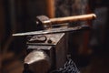 Closeup of a blacksmith anvil with a hammer, tongs, firesteel and flint.