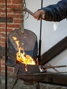 A closeup of a blacksmith fanning a flame with leather bellows