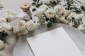 Closeup of blank greeting card. Moody wedding table mockup scene. Feminine desktop composition with fading white rose