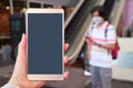 Closeup blank mobile phone screen in woman`s hand with blurry man wearing face mask to prevent infection in the backdrop