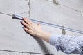 Closeup blonde girl designer foreman in white construction helmet measures the grey wall of sibit by tape measure in house under