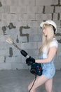 Closeup blonde girl foreman in white construction helmet holding professional perforator, drill in house under construction. Royalty Free Stock Photo