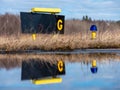 Closeup of a blue airport taxiway light with taxiway G sign in the background. Reflection on the water Royalty Free Stock Photo