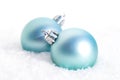 Closeup of blue Christmas bulbs in the snow in front of a blurry background Royalty Free Stock Photo