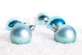 Closeup of blue Christmas bulbs in the snow in front of a blurry background Royalty Free Stock Photo