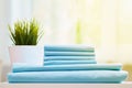 Closeup of blue clean bedding on a blurred background. A stack of folded new bed sheets on the table.