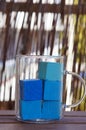 Closeup of blue-colored bathing cubes in a glass mug on the table