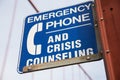 Closeup of a blue [Emergency Phone And Crisis Counseling] sign on a bridge with a blurry background Royalty Free Stock Photo