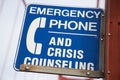 Closeup of a blue [Emergency Phone And Crisis Counseling] sign on a bridge with a blurry background Royalty Free Stock Photo