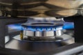 Closeup blue flame from a gas stove burner. Stainless steel kitchen surface with cast-iron grill. Royalty Free Stock Photo