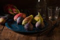 Closeup of a blue plate full of figs, prickly pears with dragon fruit, fork, knife and empty glasses Royalty Free Stock Photo