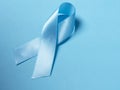 Closeup a Blue satin Ribbon symbol of prostate cancer awareness on a bright blue background. Royalty Free Stock Photo