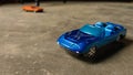 Closeup of blue toy car for children on diverse background with orange toy car on background. Royalty Free Stock Photo