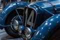 Closeup of the blue, vintage Delahaye 135 racecar in front of a three-quarter view