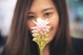 Closeup blur image of a beautiful Asian woman looking at a pink Siam Tulip flower