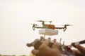 Closeup of blurred hands operating drone transmitter, receiver controller, controller in out of focus while drone is in focus at Royalty Free Stock Photo