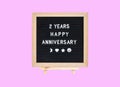 Closeup a board with 2 years happy anniversary word isolated on pink background