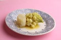 Closeup of boiled romanesco broccoli with potatoes in a plate on a pink surface