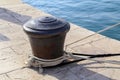 Closeup of a bollard with a mooring line wrapped around it