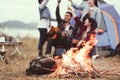 Closeup of bonfire and friendship clinking drinking bottle glass for celebrating in party with mountain meadow and lake view Royalty Free Stock Photo