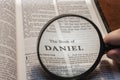 closeup of the book of Daniel from Bible or Torah using a magnifying glass to enlarge print.