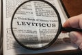 closeup of the book of Leviticus from Bible or Torah using a magnifying glass to enlarge print.