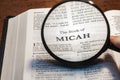 closeup of the book of Micah from Bible or Torah using a magnifying glass to enlarge print.