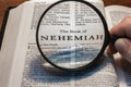 closeup of the book of Nehemiah from Bible or Torah using a magnifying glass to enlarge print. Royalty Free Stock Photo