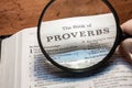 closeup of the book of Proverbs from Bible or Torah using a magnifying glass to enlarge print.
