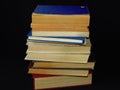 Closeup of books pile. A pile of old books is pictured against dark black background. Old books stacked in a pile.