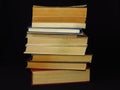 Closeup of books pile. A pile of old books is pictured against dark black background. Old books stacked in a pile.