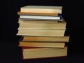 Closeup of books pile. A pile of old books is pictured against dark black background.