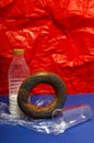 Vertical image.Bottle of milk, fresh bread roll, glass on the blue background against red background