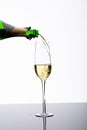 Closeup of bottle pouring champagne in flute on table against white background with copy space Royalty Free Stock Photo
