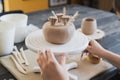 Closeup of bottom of mug, which is being decorated in ceramic studio. Female professional hands making clay dots or