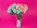 Closeup of a bouquet of artificial flowers in a vase isolated on a pink background Royalty Free Stock Photo