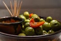 Closeup of a bowl of aceitunas, green olives and cut peppers shining from having an oily surface