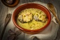 Closeup of a bowl of casserole of hake slices in green sauce with peas