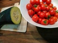 Closeup of a bowl of cherry tomatoes and squash on a wooden table