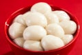 Closeup of a bowl of glutinous rice balls against a red background