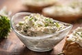 Closeup of a bowl of homemade cream cheese spread with chopped chives surrounded by bread slices with spread and a bunch