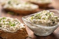 Closeup of a bowl of homemade cream cheese spread with chopped chives surrounded by bread slices with spread and a bunch