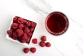 Top view and closeup of bowl of fresh and juicy raspberries, glass of sweet raspberry drink on the marble surface Royalty Free Stock Photo